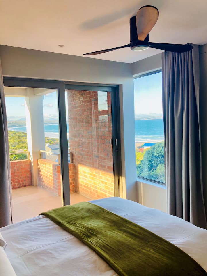 A modern, comfortable bedroom with quality linen and mattress - with a view of the ocen and direct access to the patio area