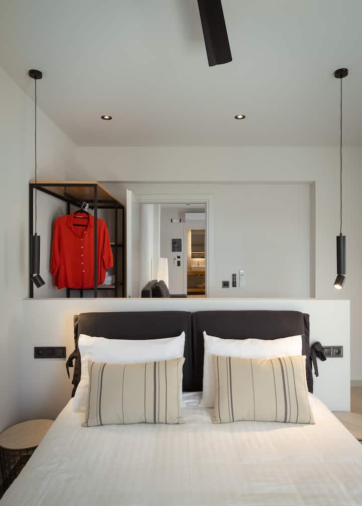 Спалнята разполага с удобно легло с плюшен матрак и меко спално бельо, предлагащо уютно и спокойно пространство за перфектен нощен сън. Простият, модерен дизайн подобрява релаксиращата атмосфера на стаята.