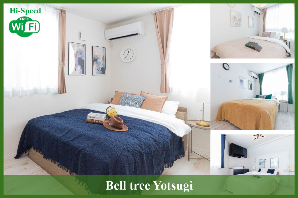 A well-appointed sleeping area displays a spacious bed dressed in dark blue blankets, complemented by light walls and natural light filtering through sheer curtains. Decorative artwork adorns the wall above, and a round clock adds a touch of functionality.