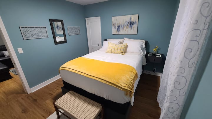 BD#1 A peaceful retreat with a cozy queen bed, gel cooling pillows, and soft bedding. The floating nightstand has LED lighting for ambiance and a charging station. The headboard has additional charging ports as well as under the bed storage drawers.