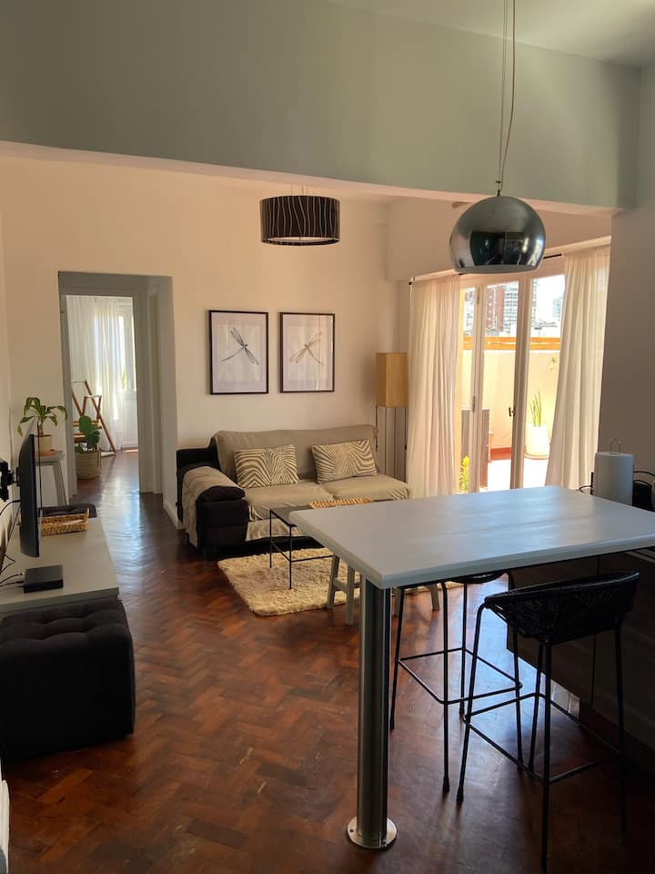 Priestranná obývacia izba prepojená s jedálňou a prístup na terasu s výhľadom a oblohou.