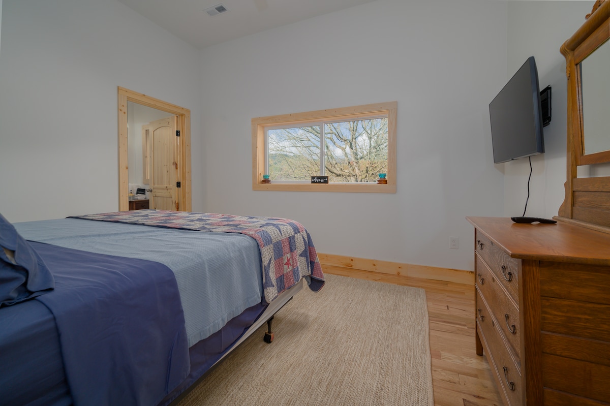 Bedroom 1 is America-inspired bedroom on the main floor features a king bed. A large window lets in natural light showcasing scenic views, while the en-suite bathroom adds modern convenience, blending comfort with timeless Americana charm.
