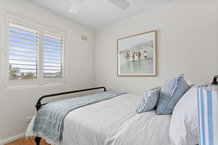 Comfortable Queen bed with wardrobe, ceiling fan and beach glimpses.