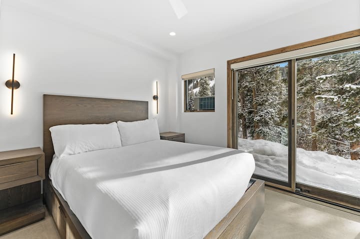 Dormitorio de invitados en el nivel inferior con una cama tamaño queen, TV y acceso al aire libre al jacuzzi. 