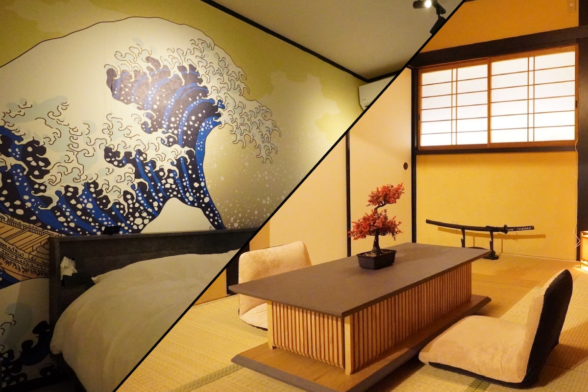 A large wall mural depicting the iconic wave from 'The Great Wave off Kanagawa' enhances the serene ambiance of the sleeping area. Adjacent is a traditional tatami room with a low wooden table and comfortable seating. Natural light filters through shoji-style windows.