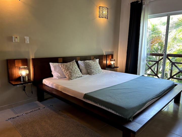 Master bedroom upstairs and cathedral ceiling, queen size mahogany bed, and window overlooking the garden and private bathroom.