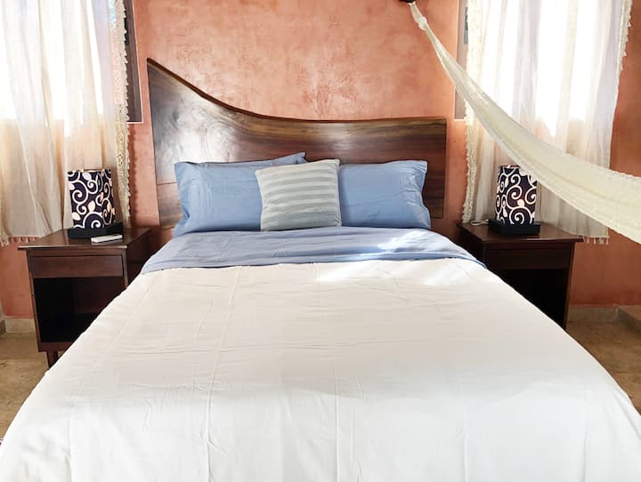 La tercera recámara tiene una cama matrimonial, mesitas de servicio con lámparas y una hamaca