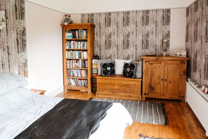 Una habitación luminosa y espaciosa con mucho espacio de almacenamiento, espejo de tocador y una animada vista al parque. Cómoda cama tamaño king . 