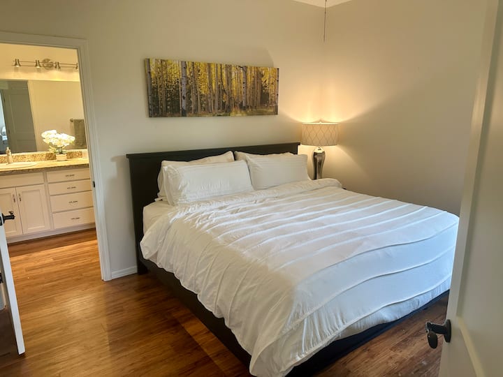 Cama tamaño king con colchón tempurpedic, mesita de noche con lámpara y aparador. Además, hay un vestidor