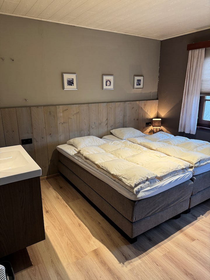 Dormitorio para 3 personas con camas de somier, lavabo y ducha.