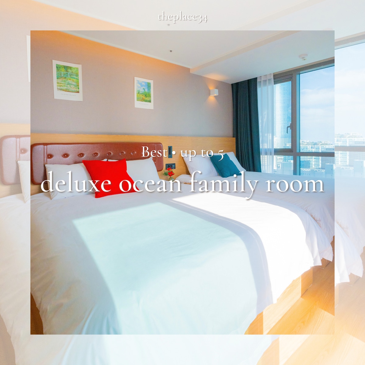 A spacious family room features two large beds with soft bedding, inviting guests to rest comfortably. Natural light fills the room through a large window, offering views of the ocean. Simple decor enhances the overall tranquility of the space.
