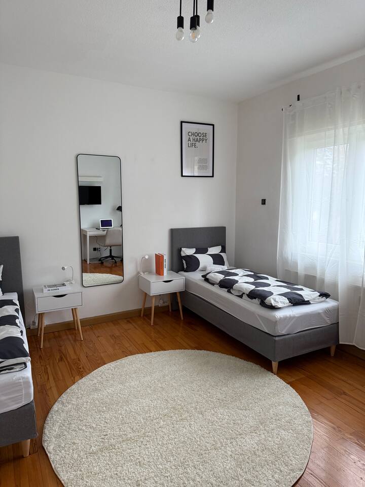 เตียงเดี่ยว 2 เตียงพร้อมโต๊ะข้างเตียงและโคมไฟข้างเตียง