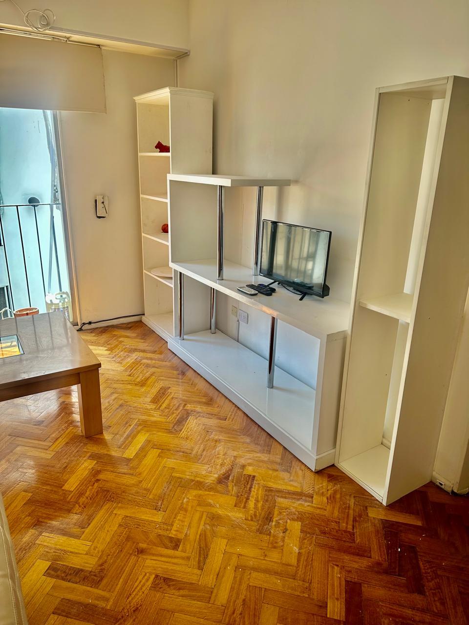 Пространа дневна соба со фотелја, втора фотелја, двојна фотелја, телевизор, излез на балконот и клима уред.