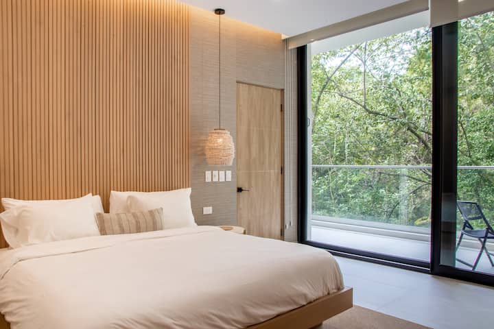 חדר שינה ראשי עם מיטת קינג סייז - הרבה ארונות ומדפים. דלתות הזזה ולוח מסך נפתחים למרפסת הפונה לג'ונגל כדי לצפות בקופים ובחיים פראיים נוספים.