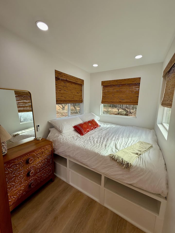 The spacious king bed, adorned with plush linens and surrounded by cozy furnishings, invites relaxation, while the remote-controlled blinds effortlessly adjust the natural light, enhancing the room's comfort and convenience.