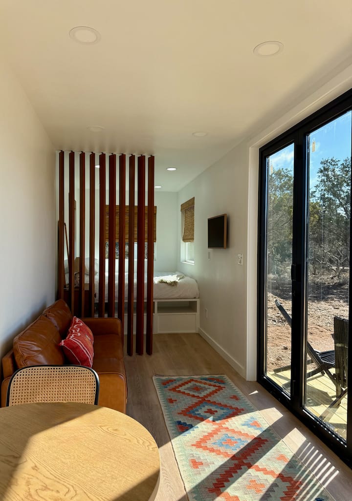 The open living room features elegantly designed swivel slats that can be adjusted to create a private bedroom space, seamlessly blending functionality with contemporary style.