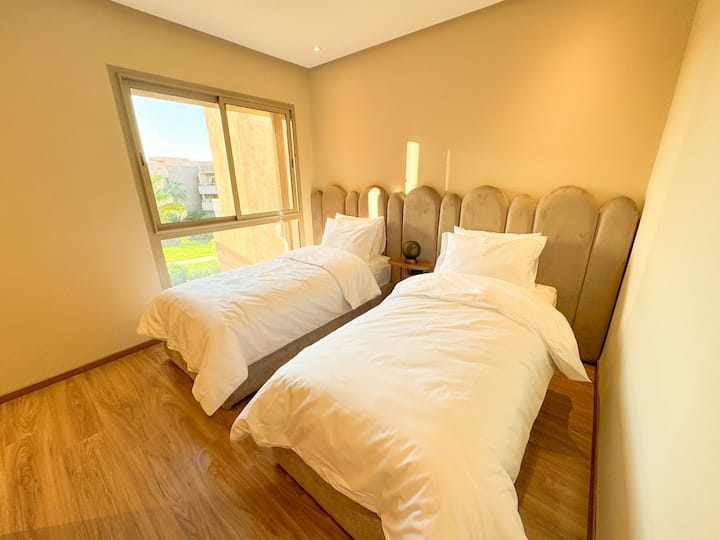 Lichte kamer met twee eenpersoonsbedden en uitzicht op de tuin