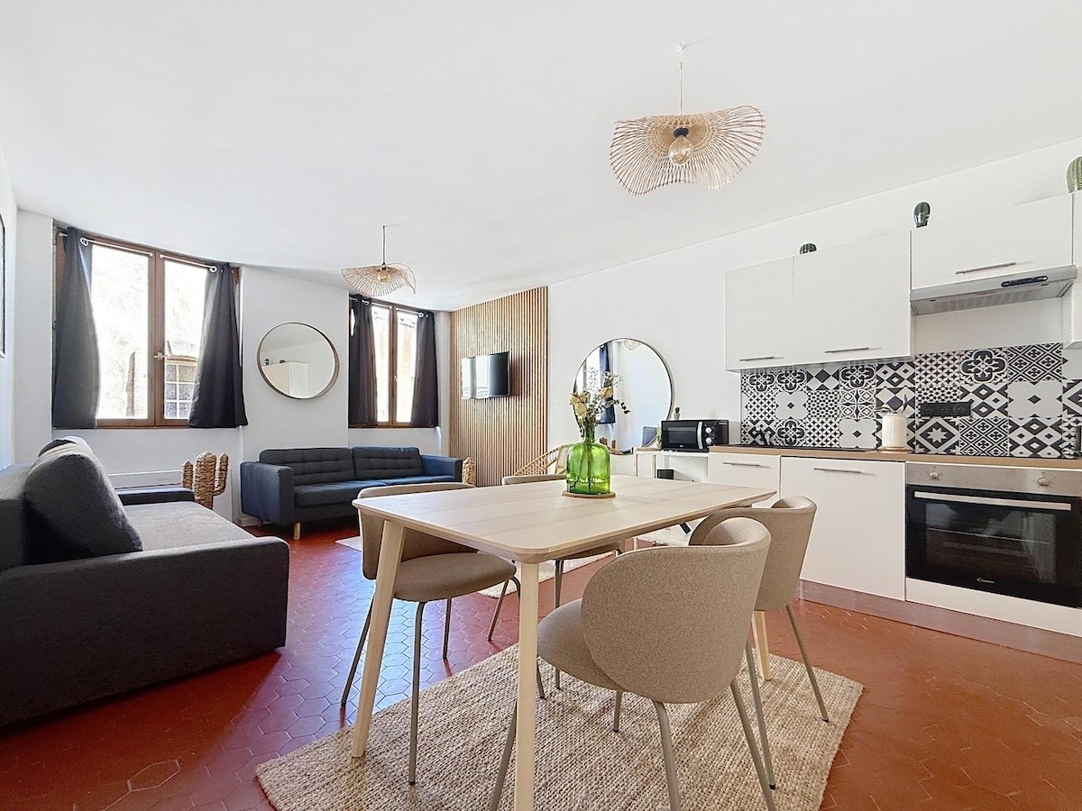 A spacious living area is featured with a stylish dining table surrounded by four chairs. The modern kitchen showcases patterned backsplash tiles, while two comfortable seating areas provide relaxation options. Large windows allow natural light to fill the space, enhancing the overall ambiance.