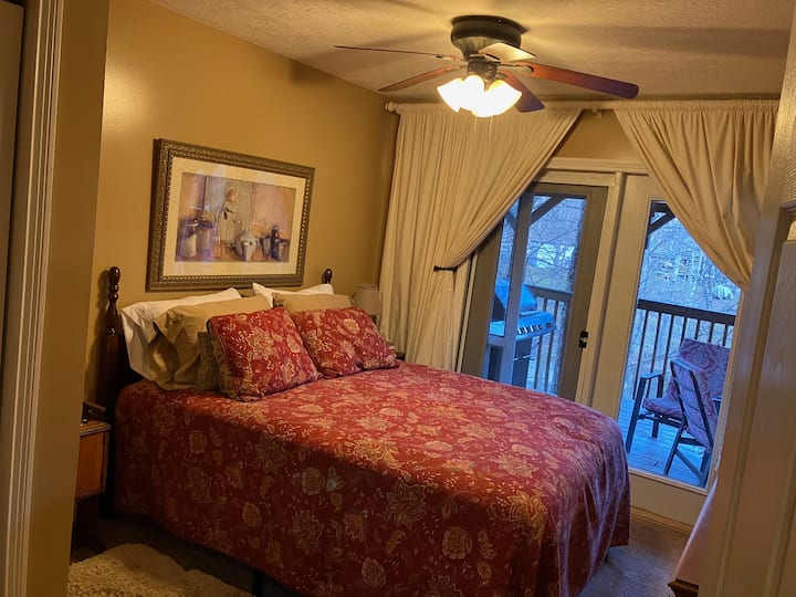 Chambre queen size à l'extérieur de l'espace de vie principal et en face de la salle de bain du premier étage. Portes-fenêtres donnant accès au porche. Il y a aussi une smart tv.