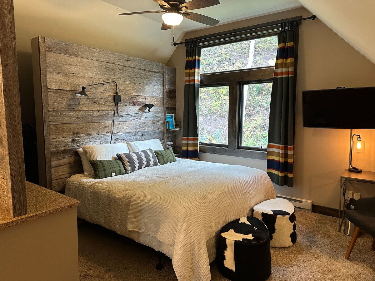 Cama king en suite principal con vista a la montaña y al baño adjunto. 