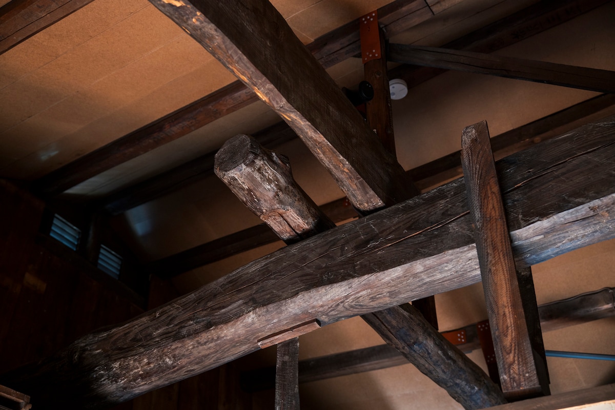 The image captures the intricate wooden beams of a traditional structure, showcasing the raw, natural beauty of aged timber. The beams highlight the architectural integrity and craftsmanship, providing a glimpse into the history and character of the space.