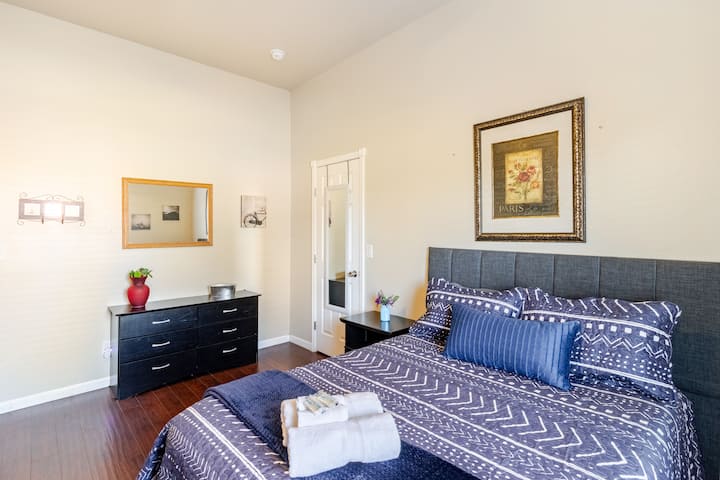 Dormitorio cómodo con ropa de cama suave, una cómoda espaciosa para el almacenamiento, televisión inteligente y un espacio de trabajo dedicado, creando un espacio tranquilo y funcional para la relajación y la productividad