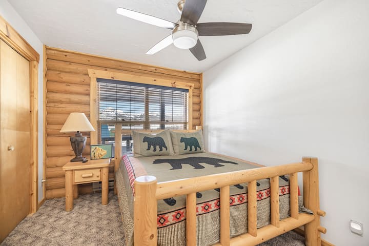 A bedroom with a queen bed and basic furnishings, set in a wood-accented space.
