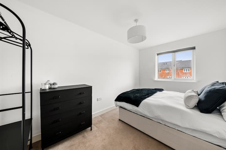 Chumba cha kulala kilicho na hanger ya rafu iliyo na viango vya mbao na sehemu kubwa ya droo yenye safu nne, inayotoa hifadhi ya kutosha na mpangilio wa nguo na vifaa.