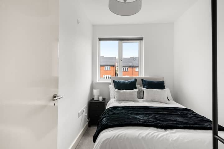 Kitanda chenye starehe cha watu wawili kilichopambwa kwa mito laini, kikiambatana na meza kando ya kitanda kwa urahisi na starehe zaidi.