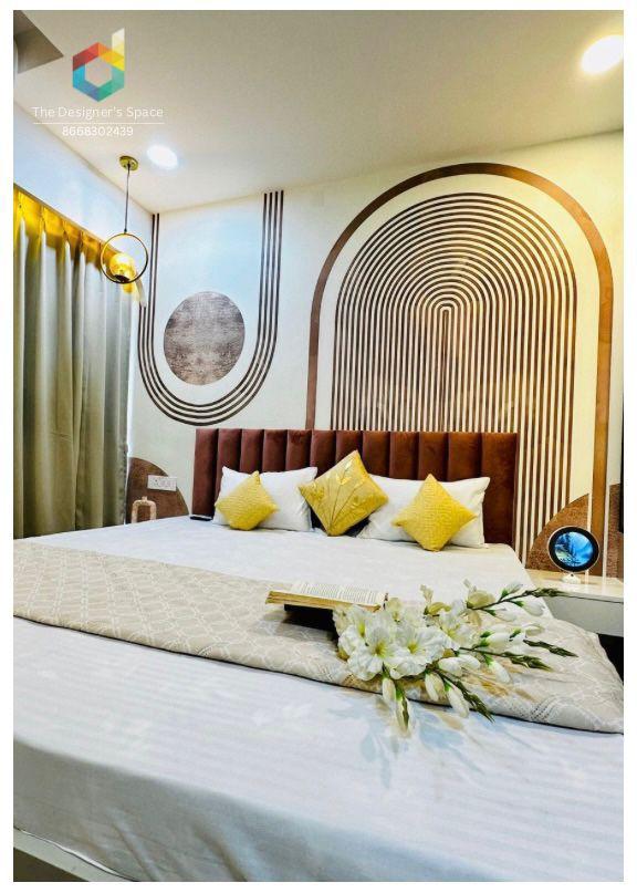 A modern sleeping area features a plush bed with decorative pillows showcasing a soothing color palette. The wall behind the bed is adorned with a stylish geometric pattern, complemented by elegant lighting fixtures. A floral arrangement adds a touch of natural beauty to the room.