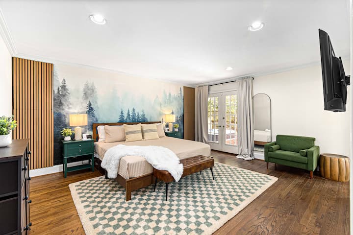 Descansa en un dormitorio sereno con una hermosa pared de acento con temática forestal, cama king y acceso privado al balcón, creando un retiro pacífico.
