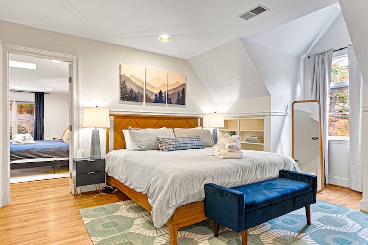 Relájate en un elegante dormitorio con una cómoda cama, asientos decorativos y vistas al entorno natural, que ofrece un retiro relajante.