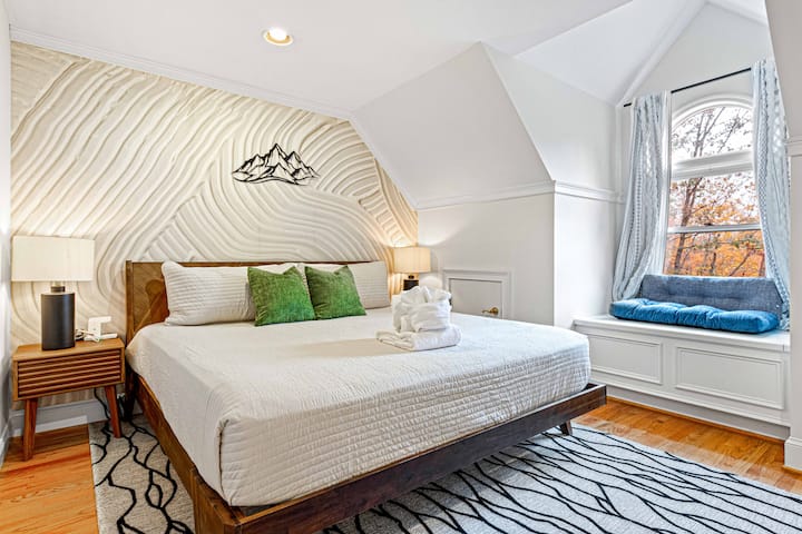 Despiértate con hermosas vistas en un acogedor dormitorio con una cama tamaño king, una pared decorativa única y un encantador rincón de ventana para momentos de lectura tranquilos.