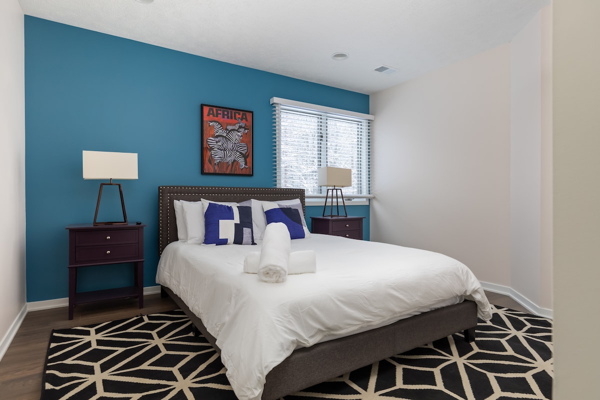 "Bedroom 6 offers a unique safari-themed ambiance with vibrant artwork and a striking accent wall. Enjoy the calming atmosphere, complemented by a lovely view of the backyard, making it a perfect space to relax and unwind."