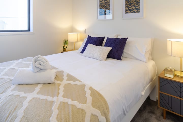 1 од 2 спални соби со отворен план со кревет во целосна големина и декоративна странична масичка и ламба