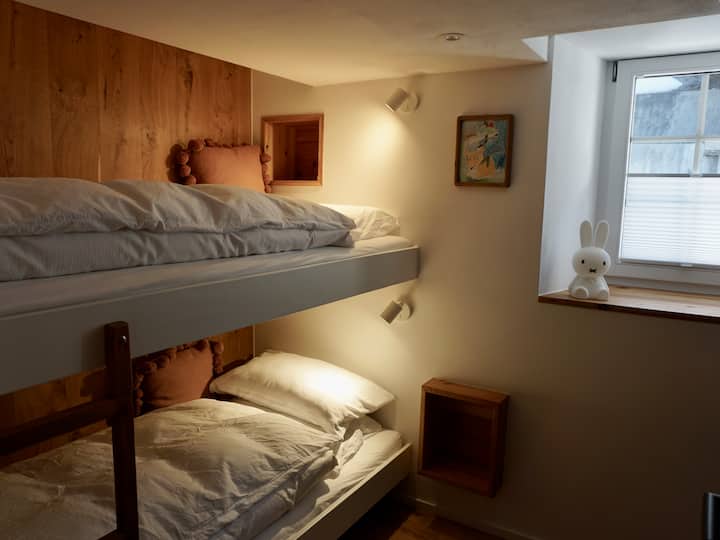 Cette chambre confortable dispose de deux lits superposés (90 x 190 cm), d'un espace de rangement, de crochets et d'une armoire juste en face de la pièce. Le joli papier peint ajoute au charme général.