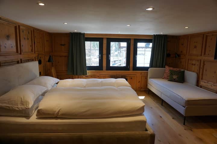 Chambre spacieuse au premier étage avec un lit double (160 x 200 cm) et un lit de jour (90 x 200 cm comme lit complet), pouvant accueillir 3 personnes au total. Les murs décorés de bois de pin suisse le rendent très chaleureux. Comprend une télévision de 55 po, une armoire et beaucoup de crochets. 