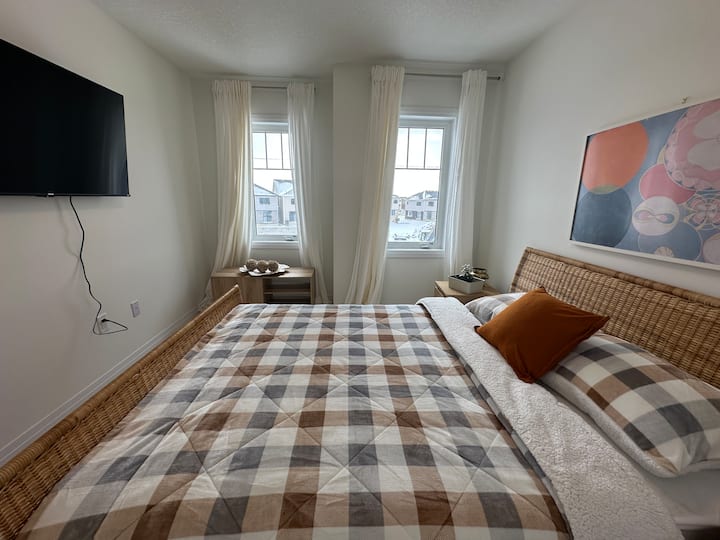 Un dormitorio cómodo y lujoso con una cama tamaño queen, dos mesas laterales, lámparas, TV de 50pulgadas y armarios.  