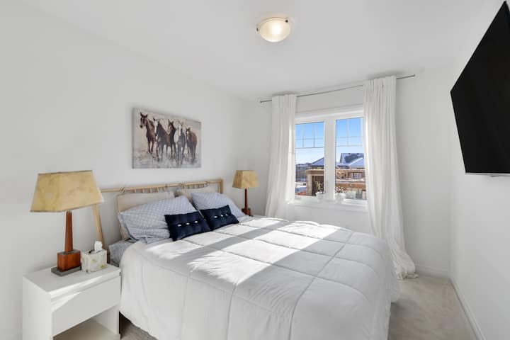 Un dormitorio cómodo y lujoso con una cama tamaño queen, dos mesas laterales, lámparas, TV de 50pulgadas y armarios.  