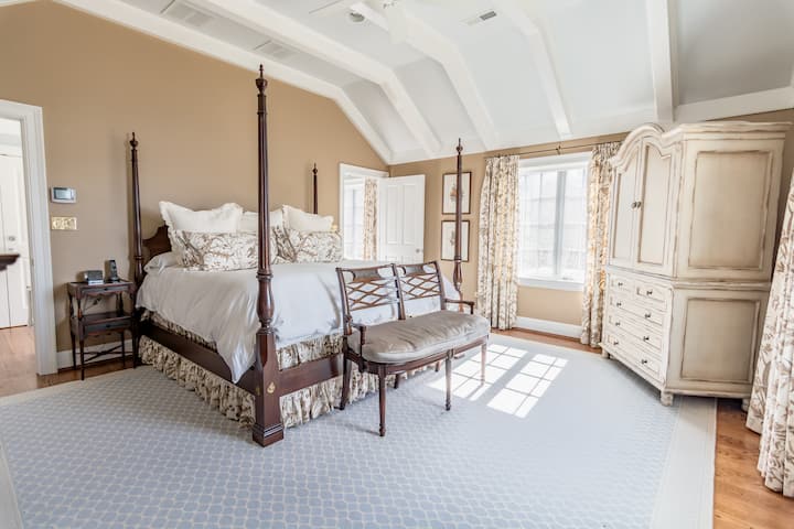 (Upstairs) Spacious primary bedroom with luxurious king bed, TV, dresser, and private attached bath