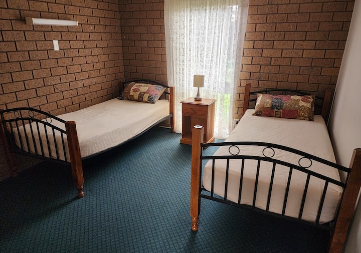 两张单人床、底部床上用品、枕头、床头柜、床上荧光灯、触摸灯、遮光窗帘、地毯地板。