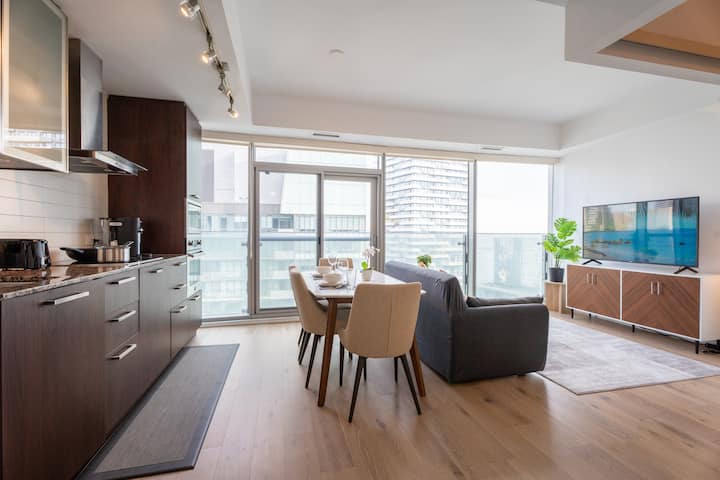 Priestranná a štýlová obývacia izba s otvoreným konceptom vás pozýva na oddych s modernou výzdobou, útulným posedením a výhľadom na balkón Julie.