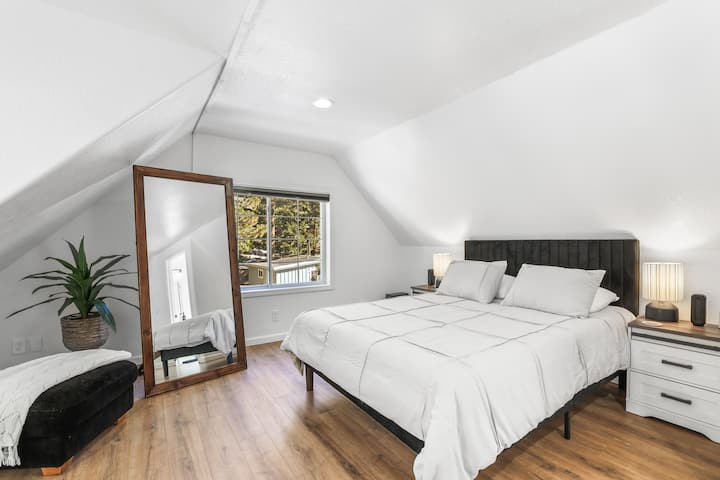 El dormitorio principal cuenta con una lujosa cama tamaño queen, un elegante televisor moderno, un gran espejo y un baño privado en suite para la máxima comodidad y conveniencia.