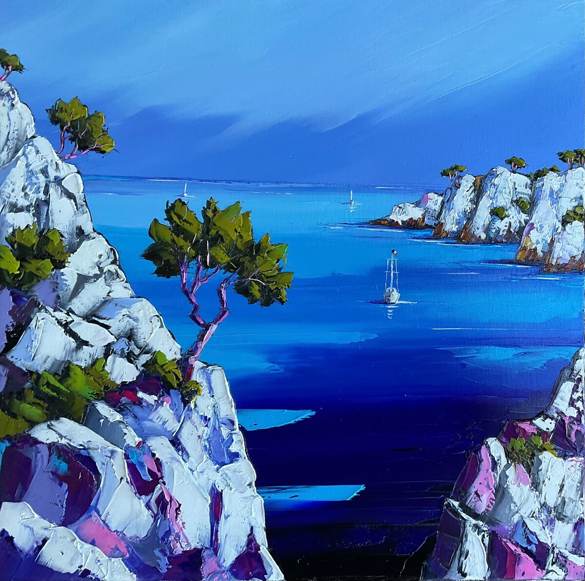 A vibrant painting depicts rocky cliffs adorned with greenery, overlooking a serene sea. The blue waters reflect the sky, while sailboats are seen in the distance, contributing to a tranquil coastal landscape.