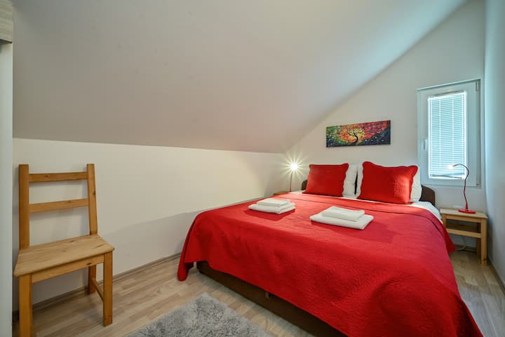 红色阁楼房间配有一张标准双人床—阁楼下的大胆色调和舒适的舒适性。