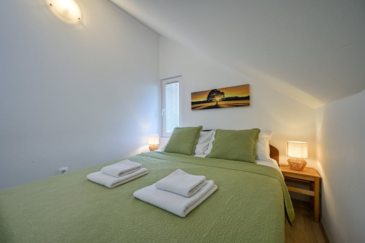 绿色阁楼房间，配有一张标准双人床—宁静的色调和乡村舒适。