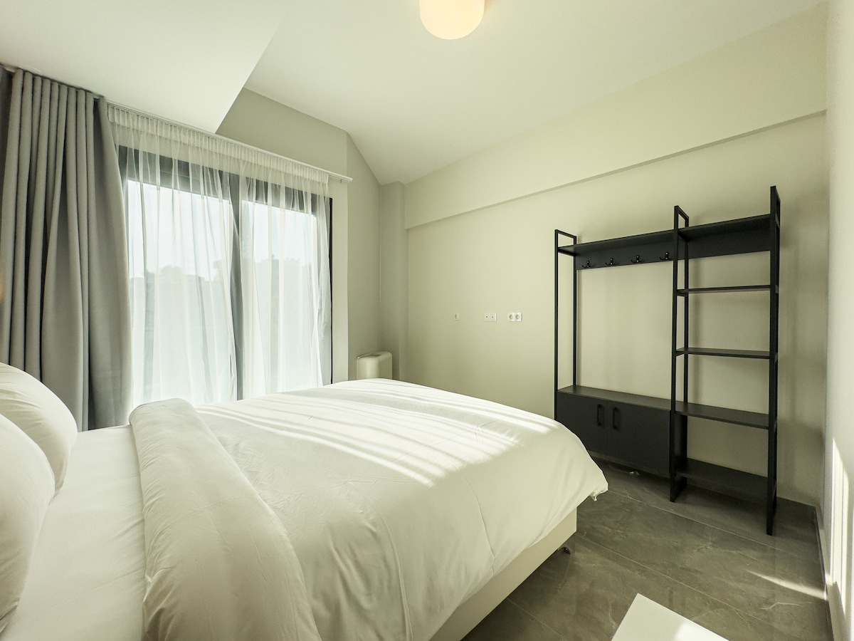 dormitorio con aire acondicionado, un armario abierto y acceso directo a un balcón. Un espacio luminoso y acogedor diseñado para la comodidad.