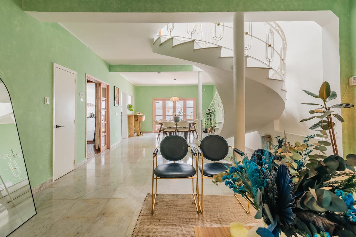 Open-plan living and dining space with marble floors and a spiral staircase at Casa Atlixco