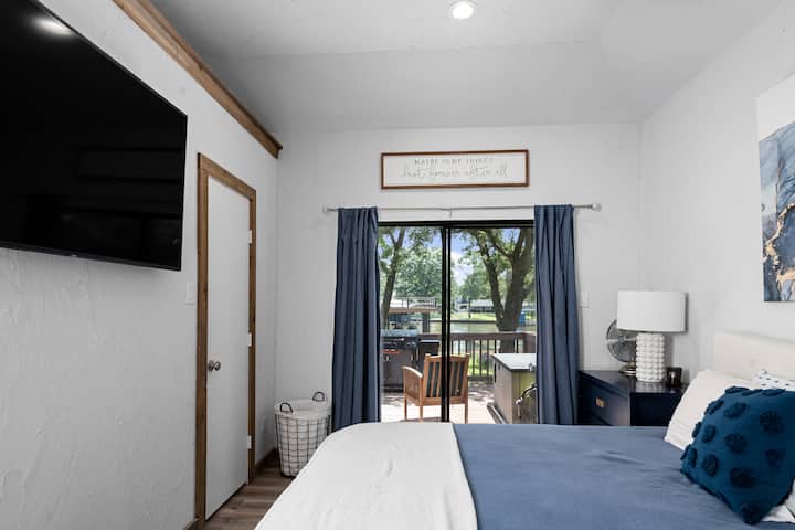 غرفة نوم رئيسية بسرير بحجم كينج مع تلفزيون وأبواب زجاجية منزلقة إلى منطقة الفناء الخارجي.