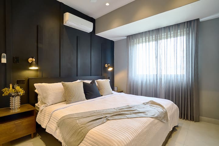 ห้องนอนใหญ่ที่น่าทึ่งมาพร้อมกับเตียงขนาด KING สุดหรูฟูกนอนระดับไฮเอนด์แอร์พัดลมเพดานม่านทึบแสงไฟโดยรอบตู้เสื้อผ้ากว้างขวางสมาร์ททีวีโต๊ะทำงานวิวเมืองที่สวยงามและห้องน้ำในตัวสุดหรูพร้อมฝักบัวอาบน้ำแบบสายฝน